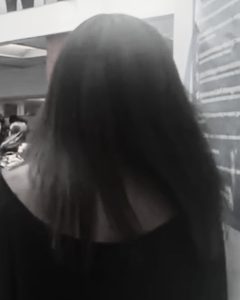 Woman walking through a school hallway shortly before discovering heat damage in her hair.